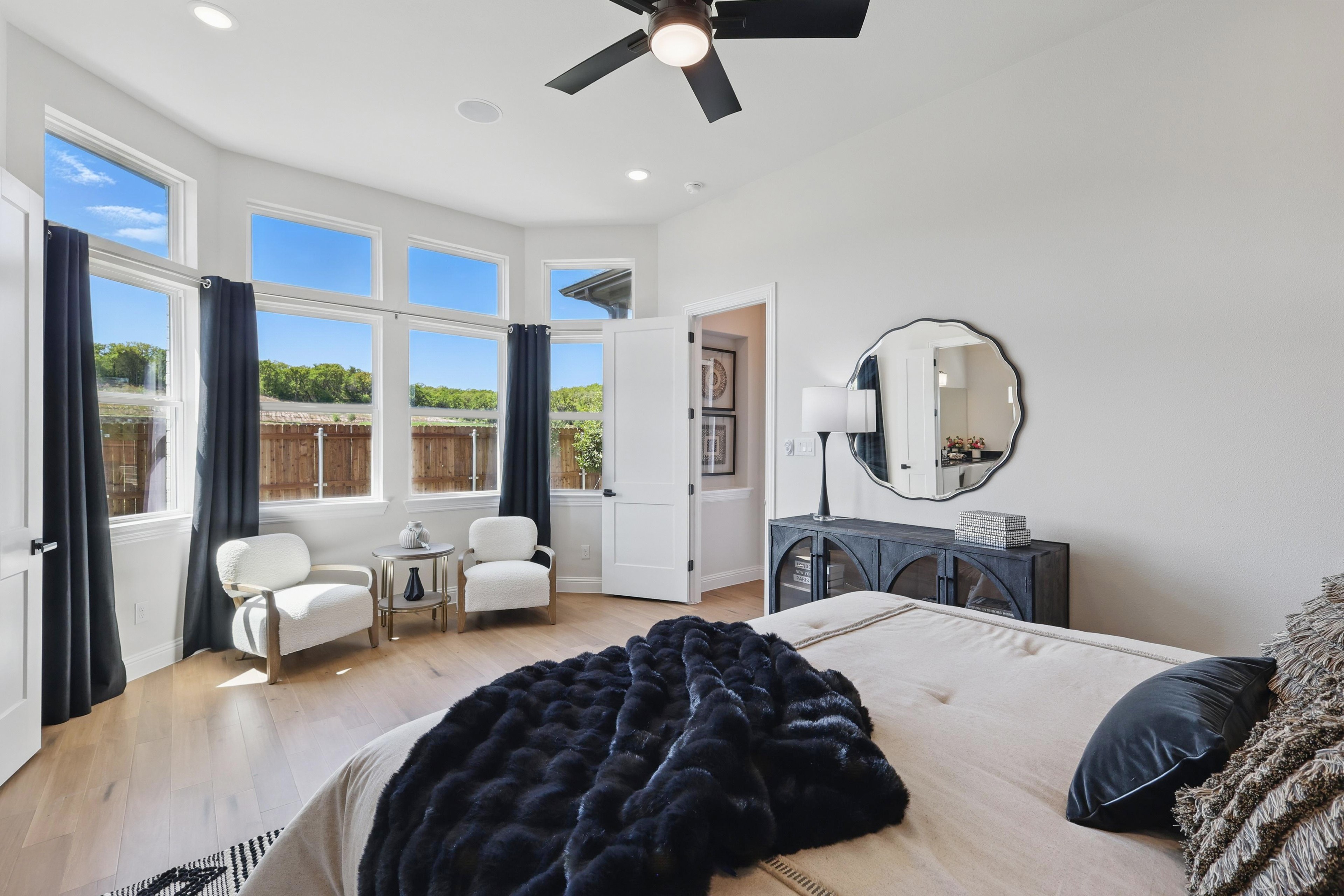 Luxurious bedroom with large windows, modern decor, and hardwood floors in Green Oaks Preserve.