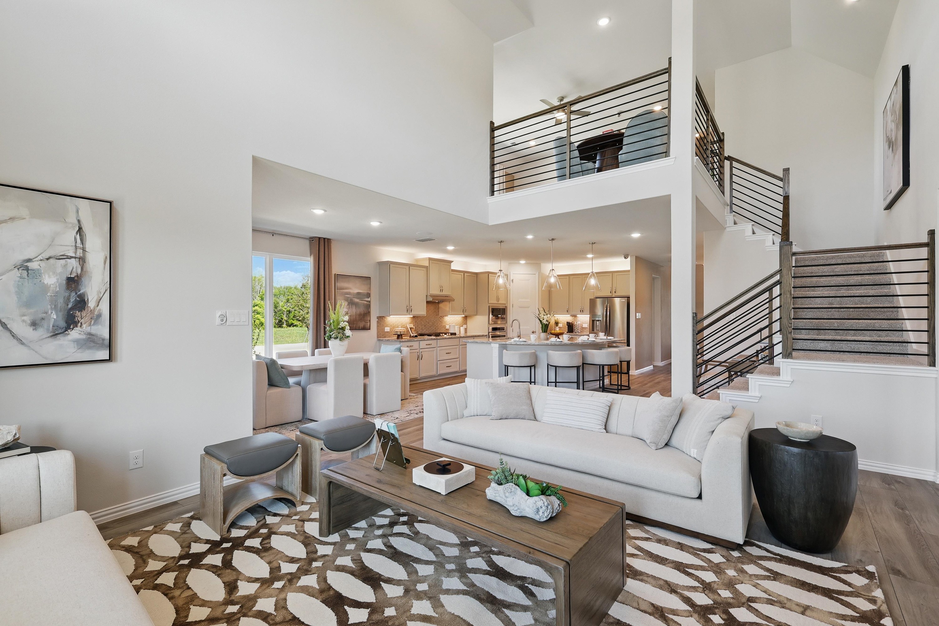 Modern living room with vaulted ceiling, open-plan kitchen, and stylish staircase in Green Oaks Preserve.