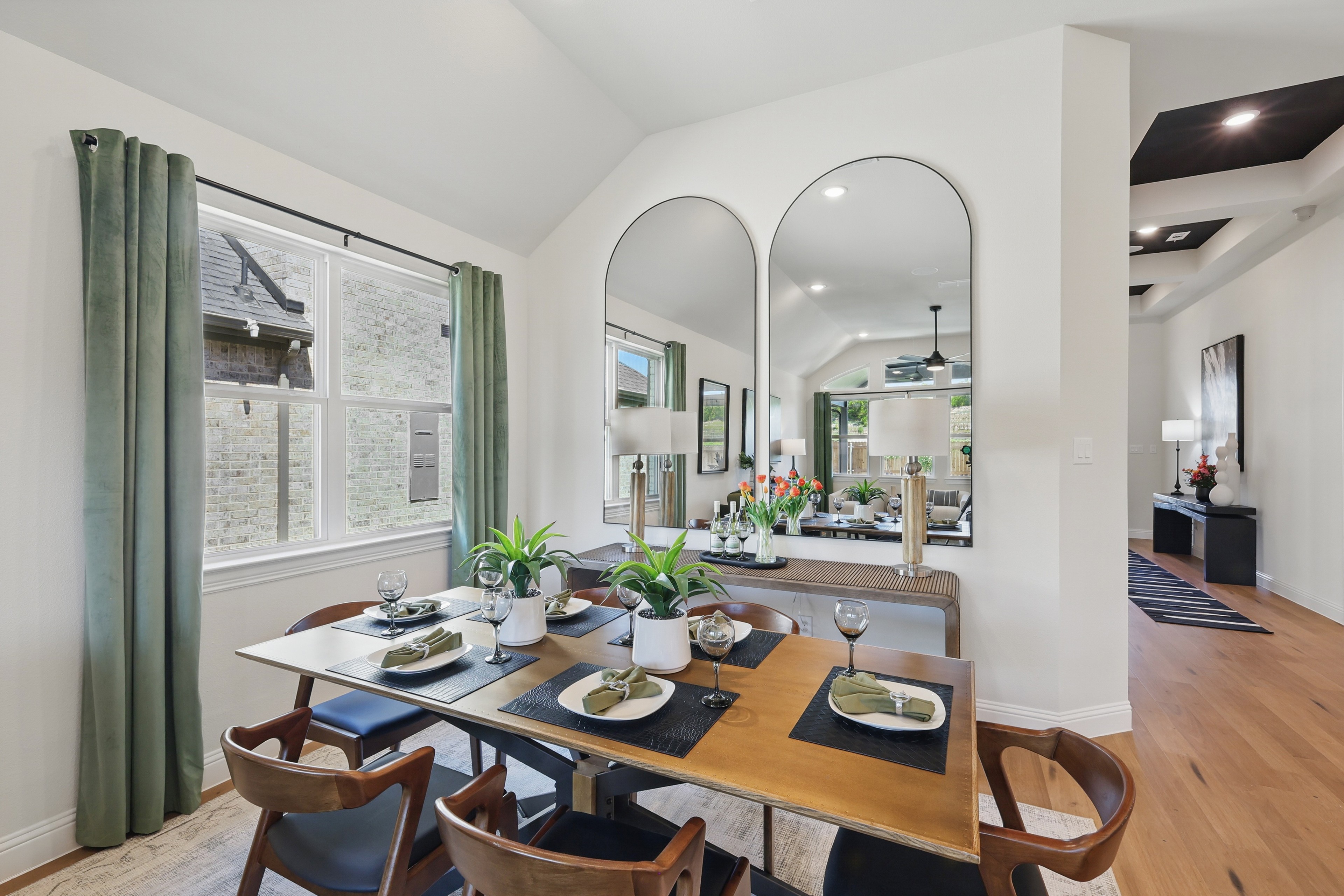 Elegant dining room with vaulted ceiling, large mirrors, and green curtains. Green Oaks Preserve community.