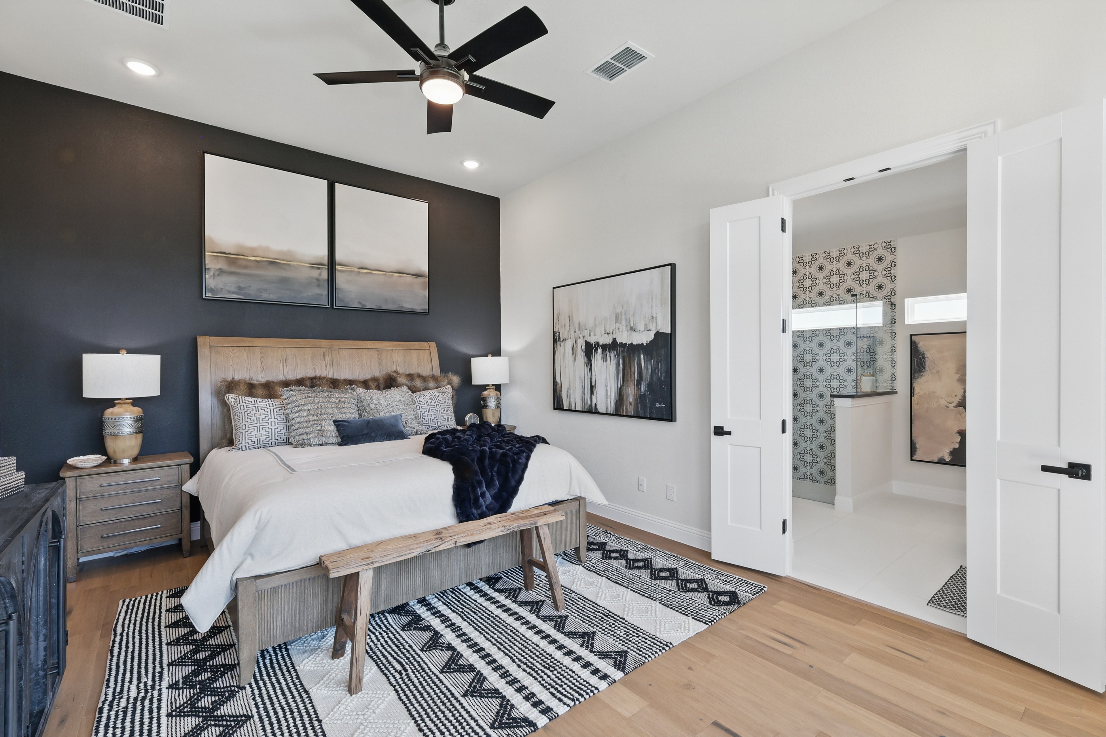 Elegant Green Oaks Preserve bedroom with modern art, wood elements, and ensuite bathroom.