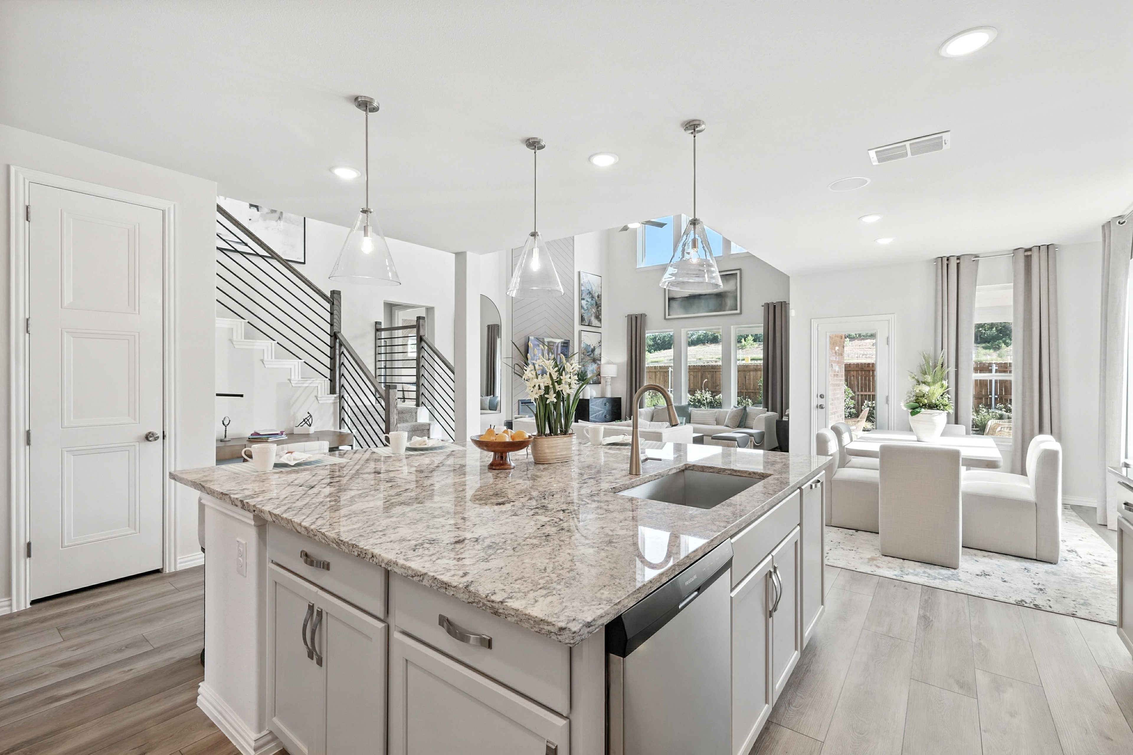 Luxurious open-plan kitchen with granite island, modern pendant lights, and high ceilings in Green Oaks Preserve.