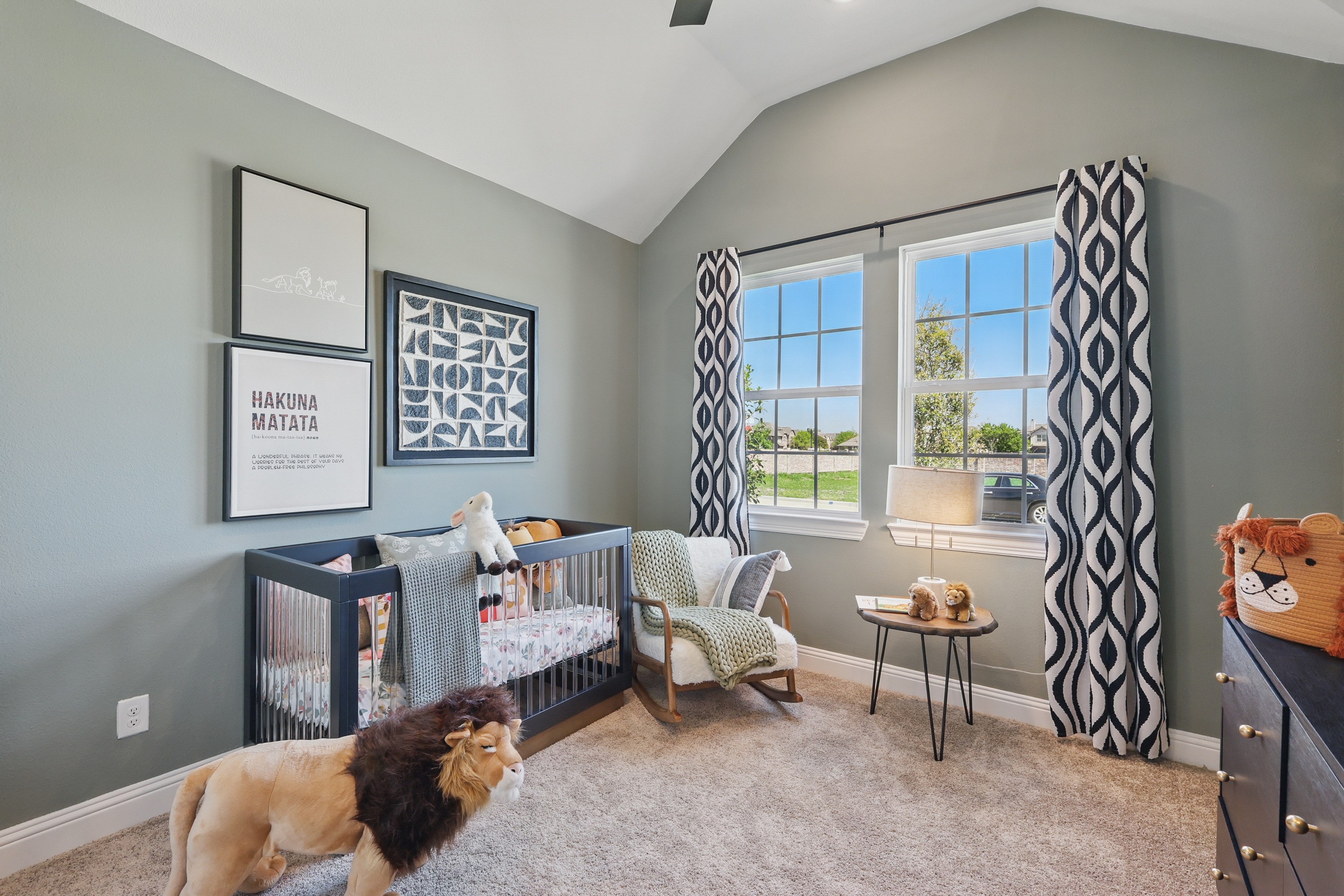 Nursery with lion plush, stylish artwork, gray walls, large windows, Green Oaks Preserve home.