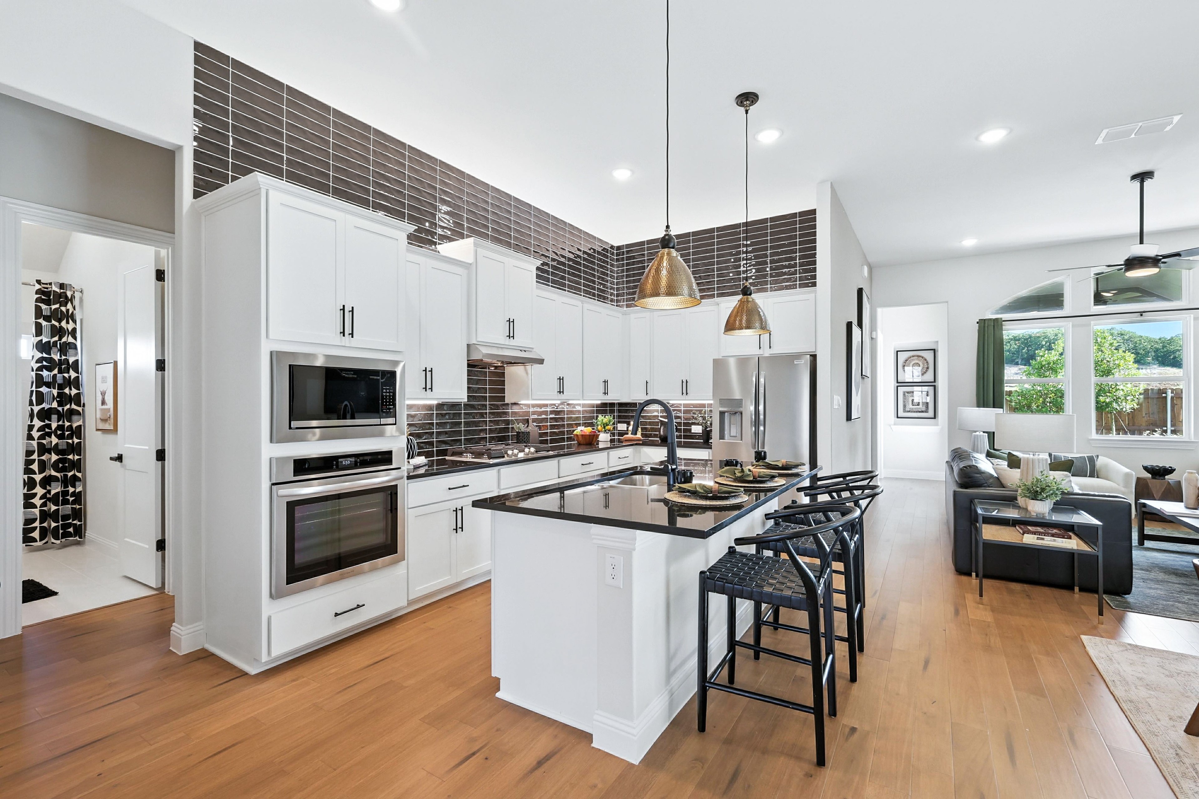 Modern kitchen with white cabinets, black countertops, pendant lights in Green Oaks Preserve home.