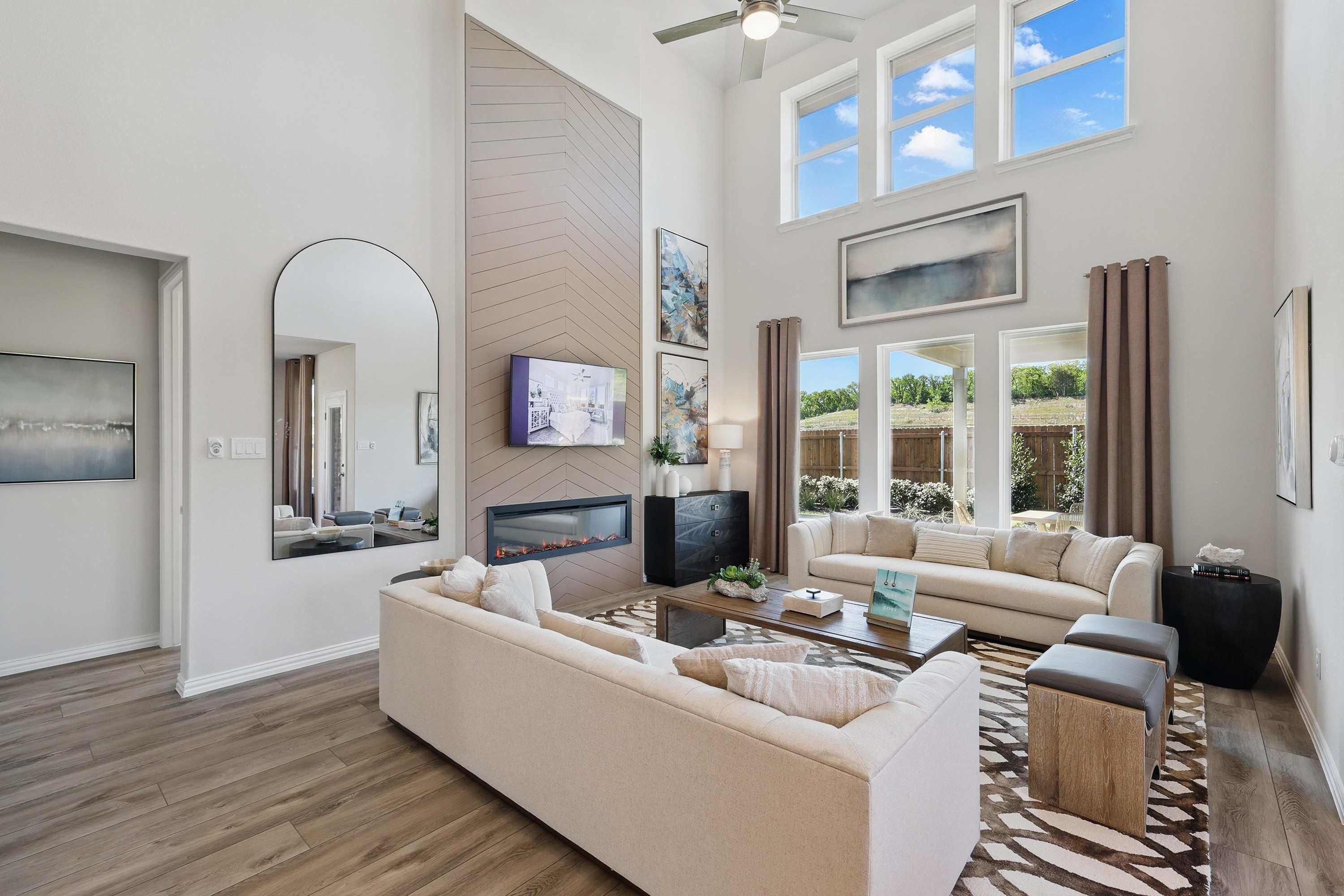 Elegant living room with high ceilings, chic fireplace, large windows in Green Oaks Preserve community.