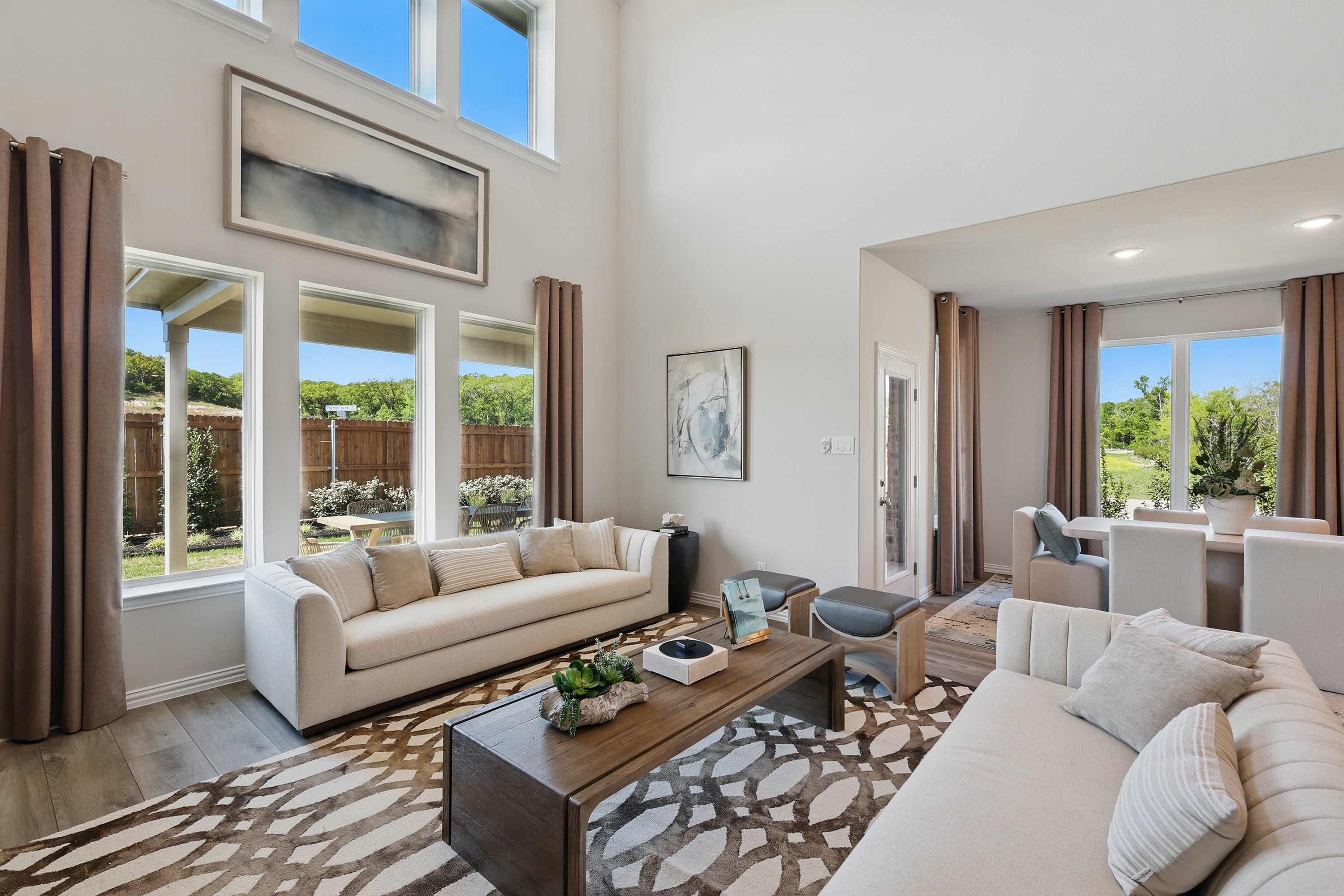 Spacious living room with tall windows, chic decor, and neutral tones in Green Oaks Preserve.
