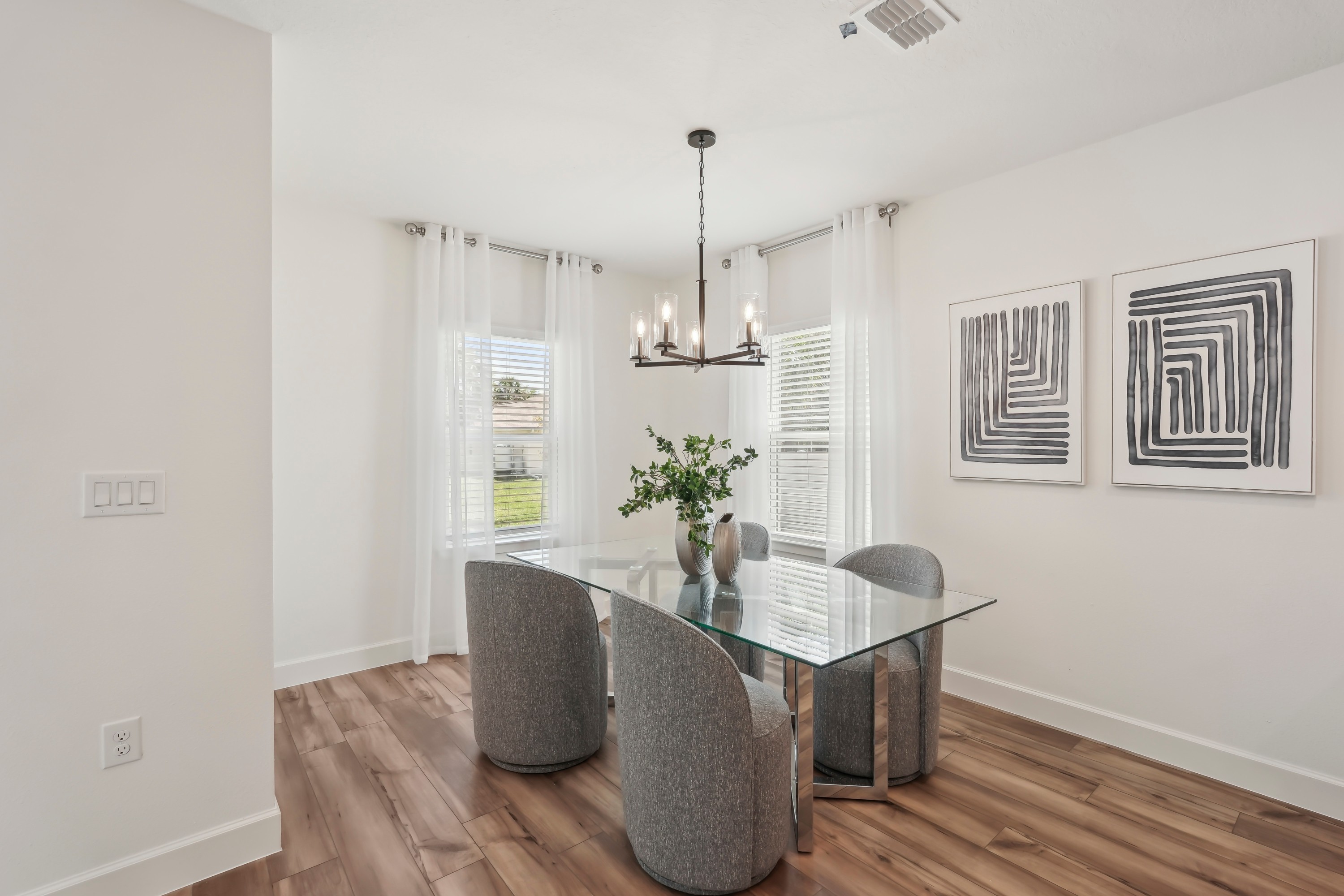 Modern dining room with glass table, wooden floor, elegant lighting in North Port.