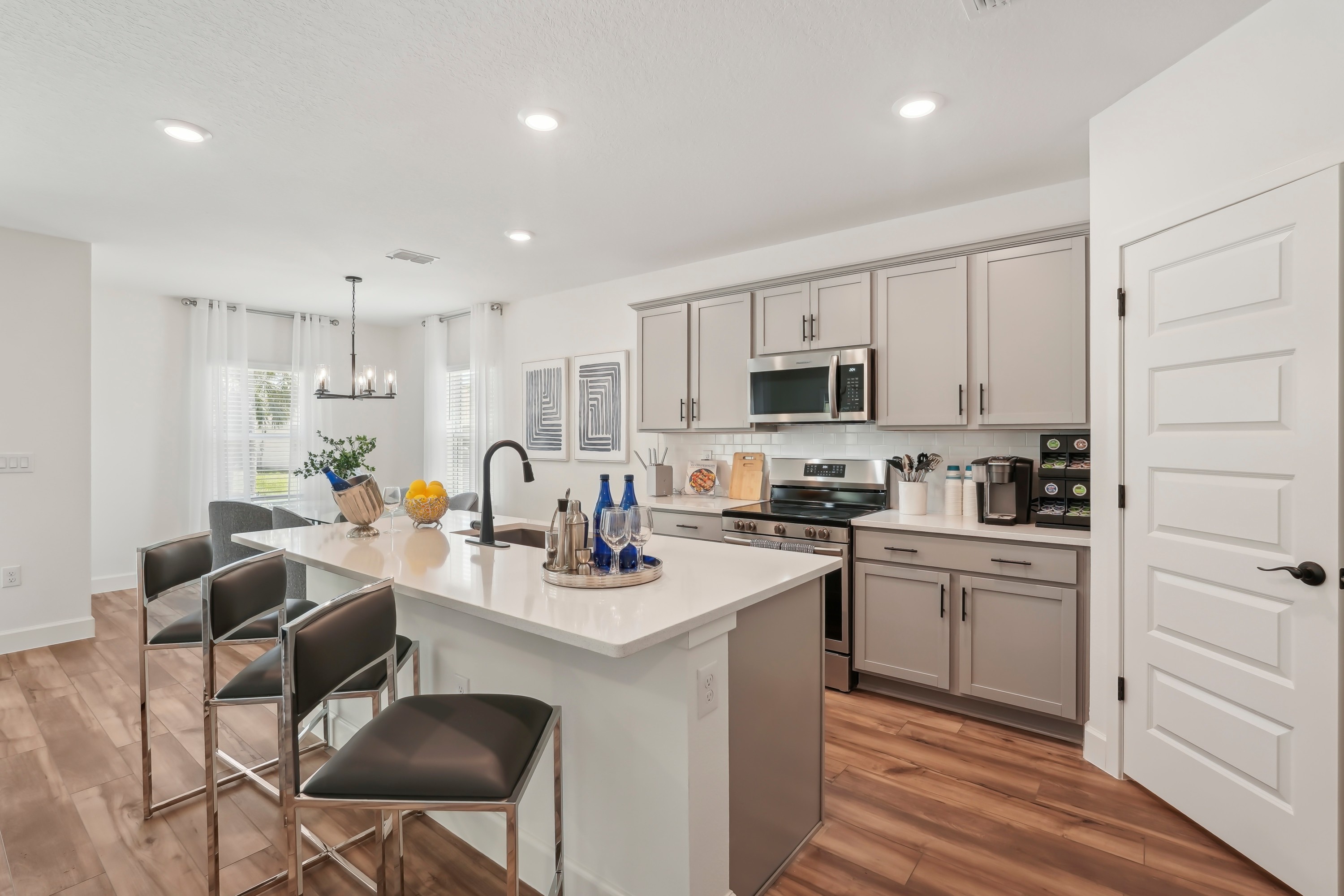 Modern North Port kitchen with white island, gray cabinets, stainless appliances, and wood floors.