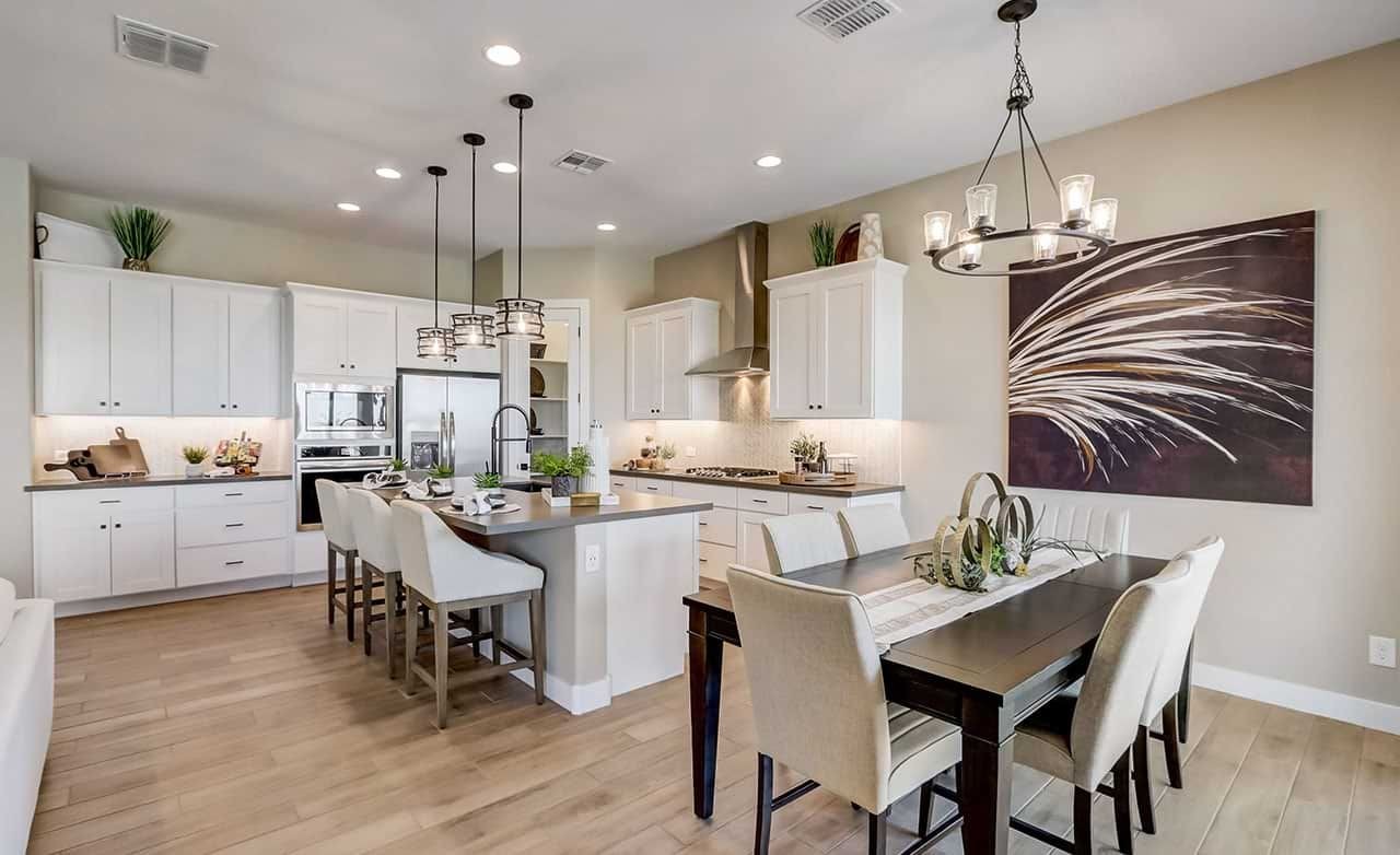 Spacious kitchen in Hacienda with white cabinets, island seating, pendant lights, and modern art.