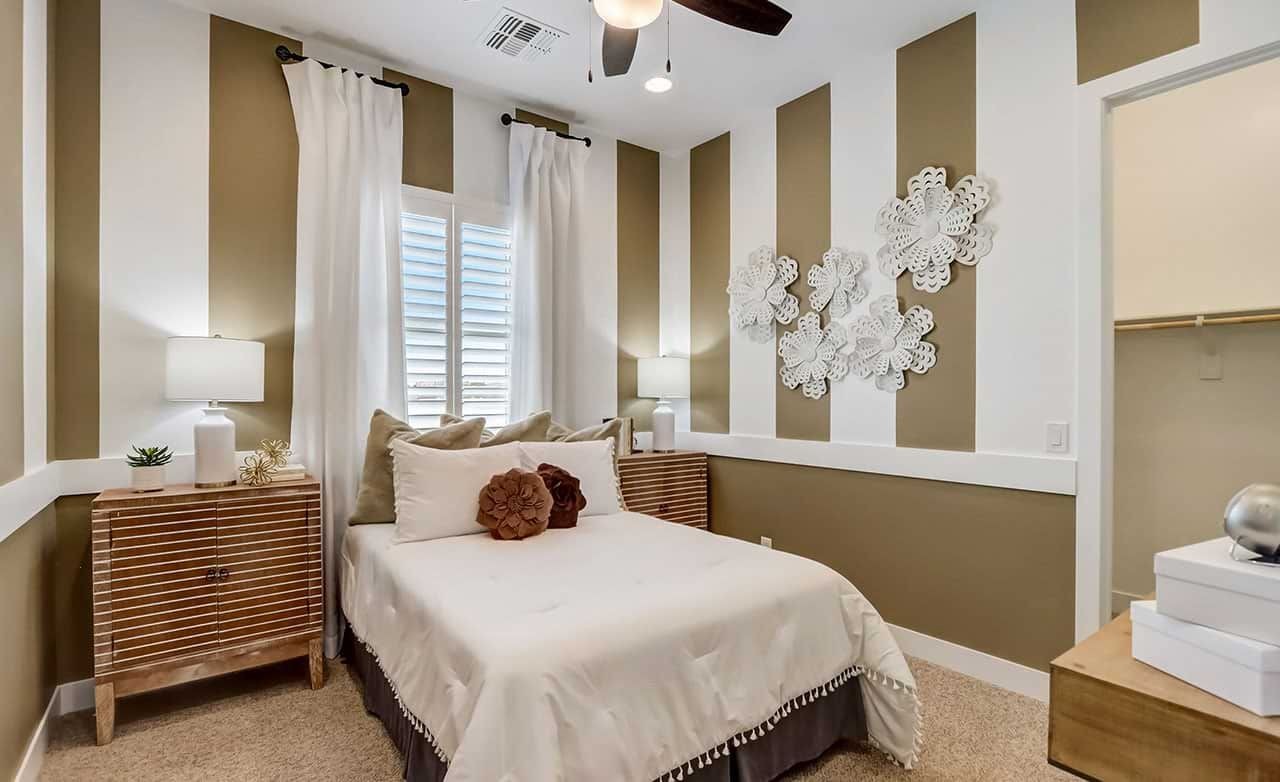 Elegant bedroom with striped walls, white bedding, ornate wall art, located in Canyon Views, Hacienda community.