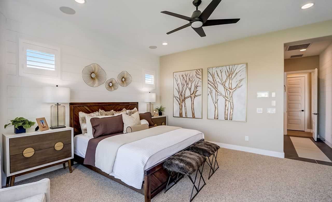 Elegant bedroom in Canyon Views with modern décor, wall art, and ceiling fan. Neutral tones and natural light.