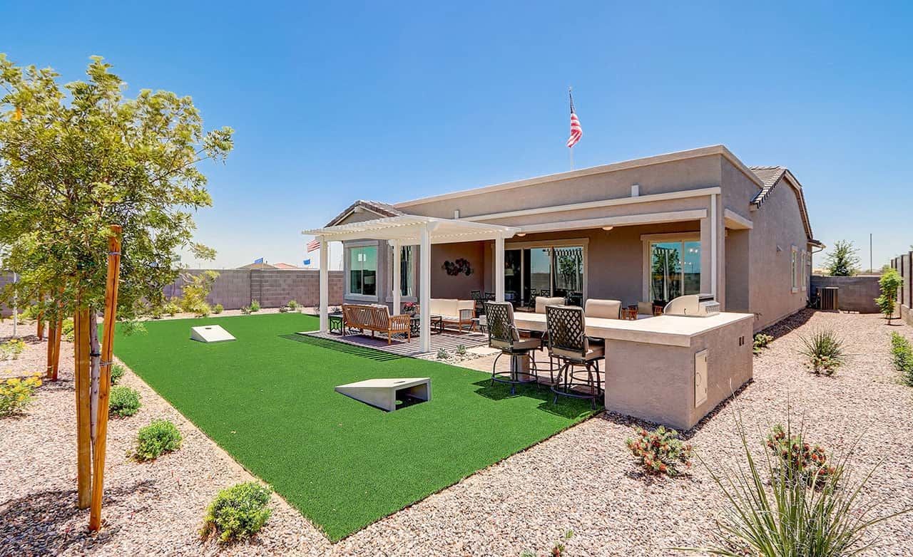 Modern home with shaded patio and artificial grass in Hacienda community, Arizona desert setting.