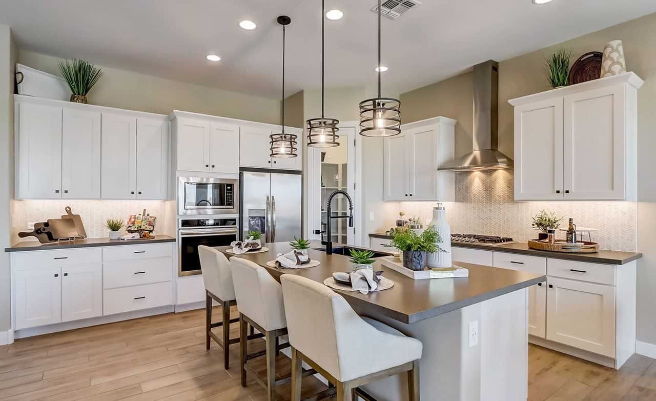 Modern kitchen with white cabinetry, island, and pendant lights in Hacienda community.