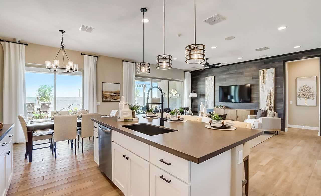 Modern kitchen and living room with wood floors, pendant lights, large windows in Canyon Views Hacienda community.