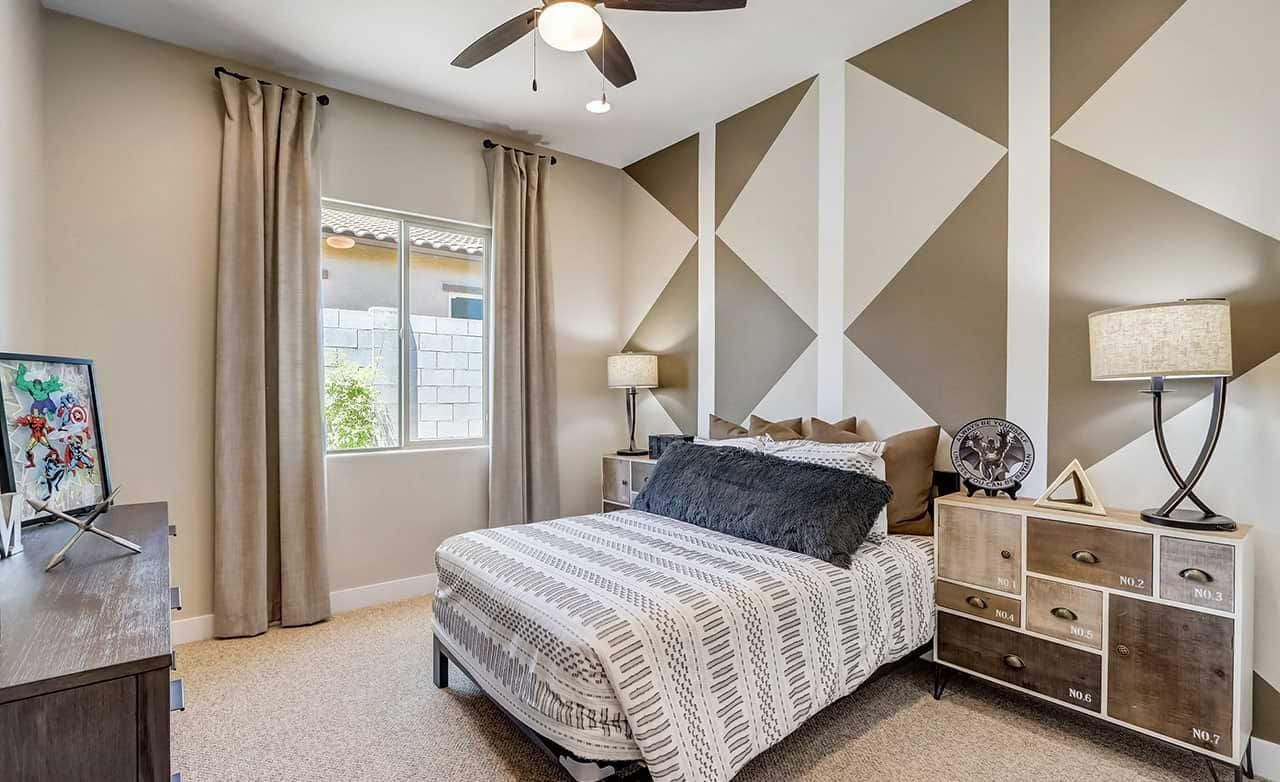Modern bedroom with geometric accent wall, elegant furniture, ceiling fan, Hacienda community.