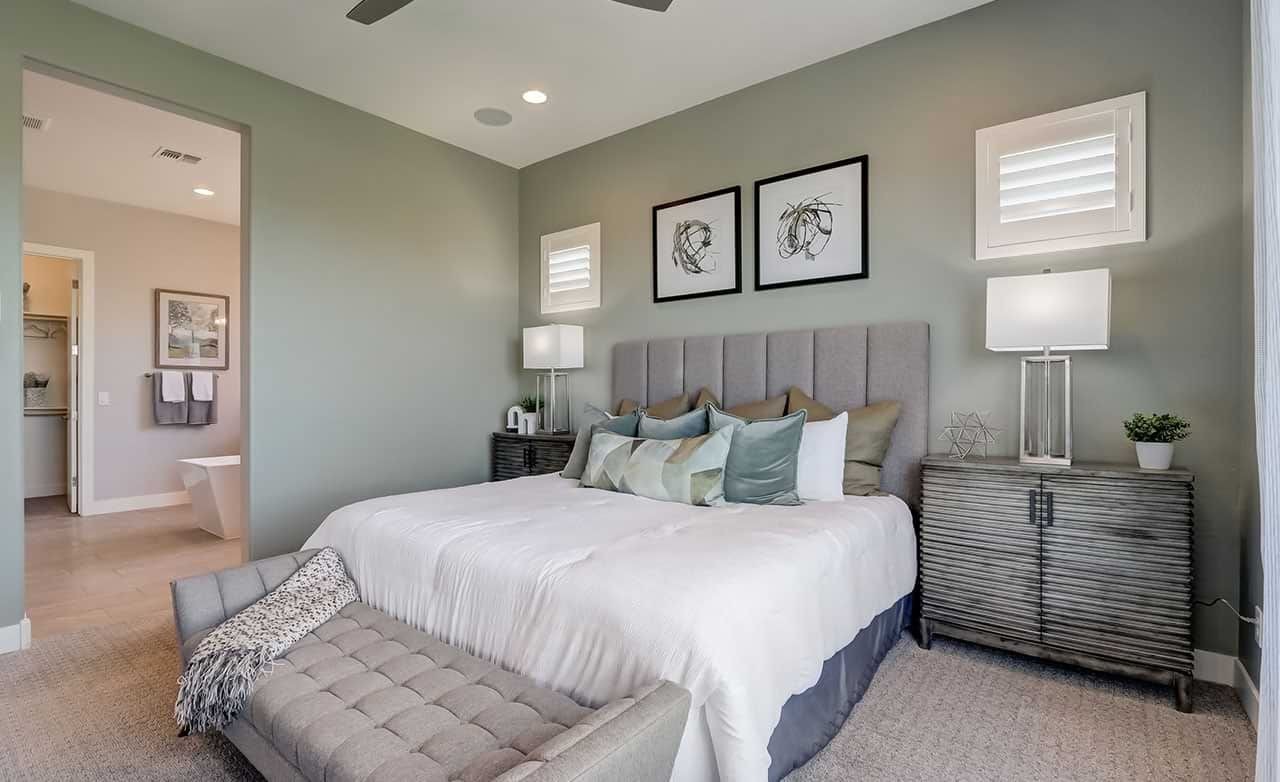 Elegant bedroom with plush bedding, gray headboard, modern art, stylish lamps in Hacienda community.