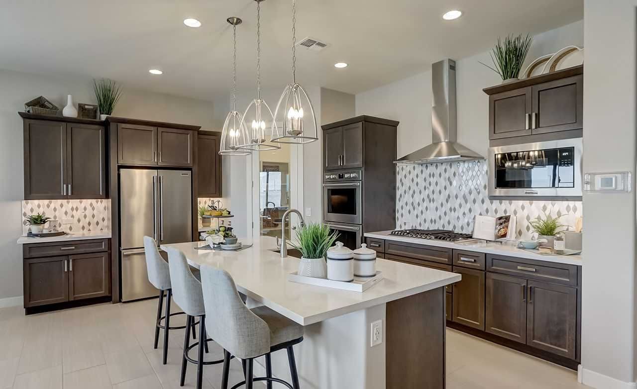 Modern kitchen with dark cabinets, island, pendant lights, stainless steel appliances in Canyon Views Hacienda community.