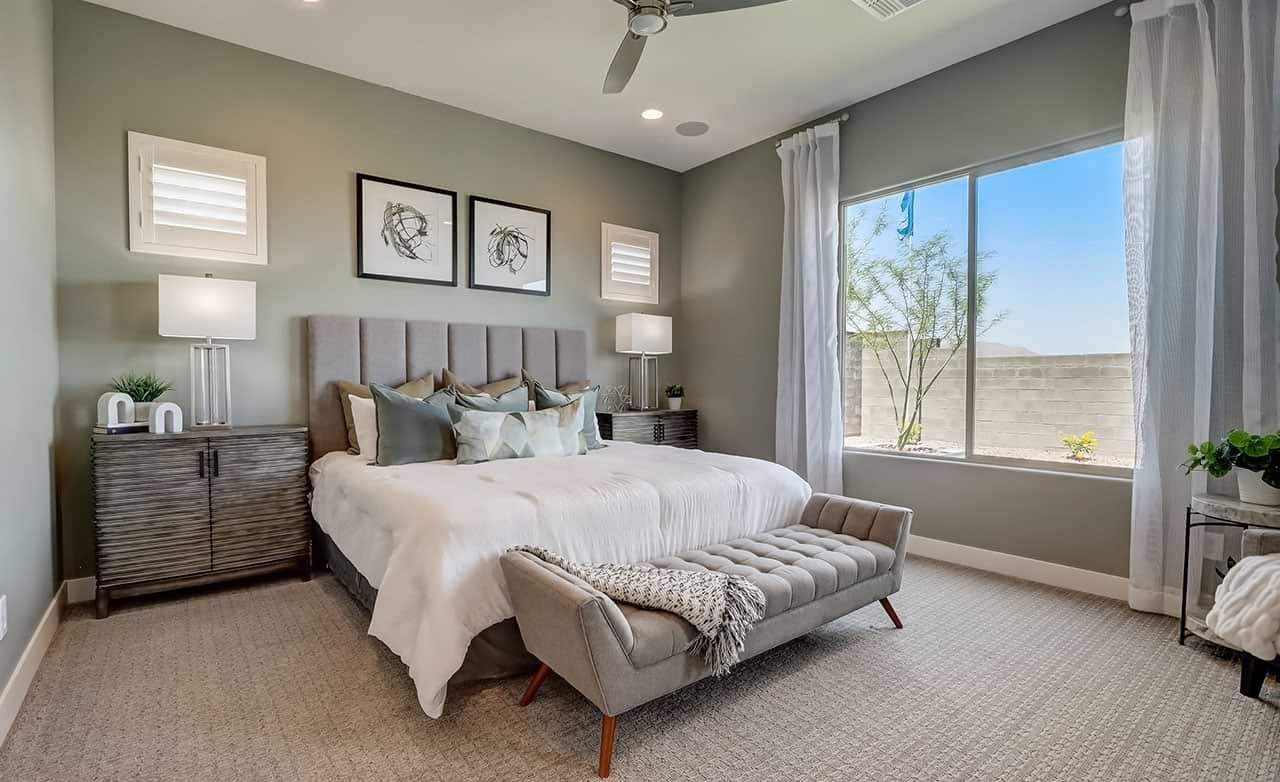 Elegant bedroom with tufted bench, plush bedding, large window, modern decor in Hacienda community, Canyon Views.