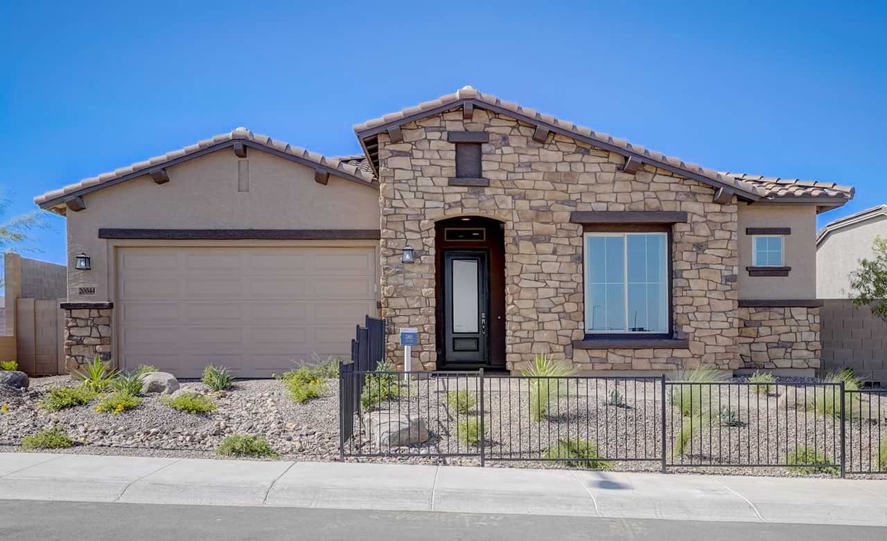 Single-story stone facade home, arched entrance, desert landscaping, Canyon Views - Hacienda community.