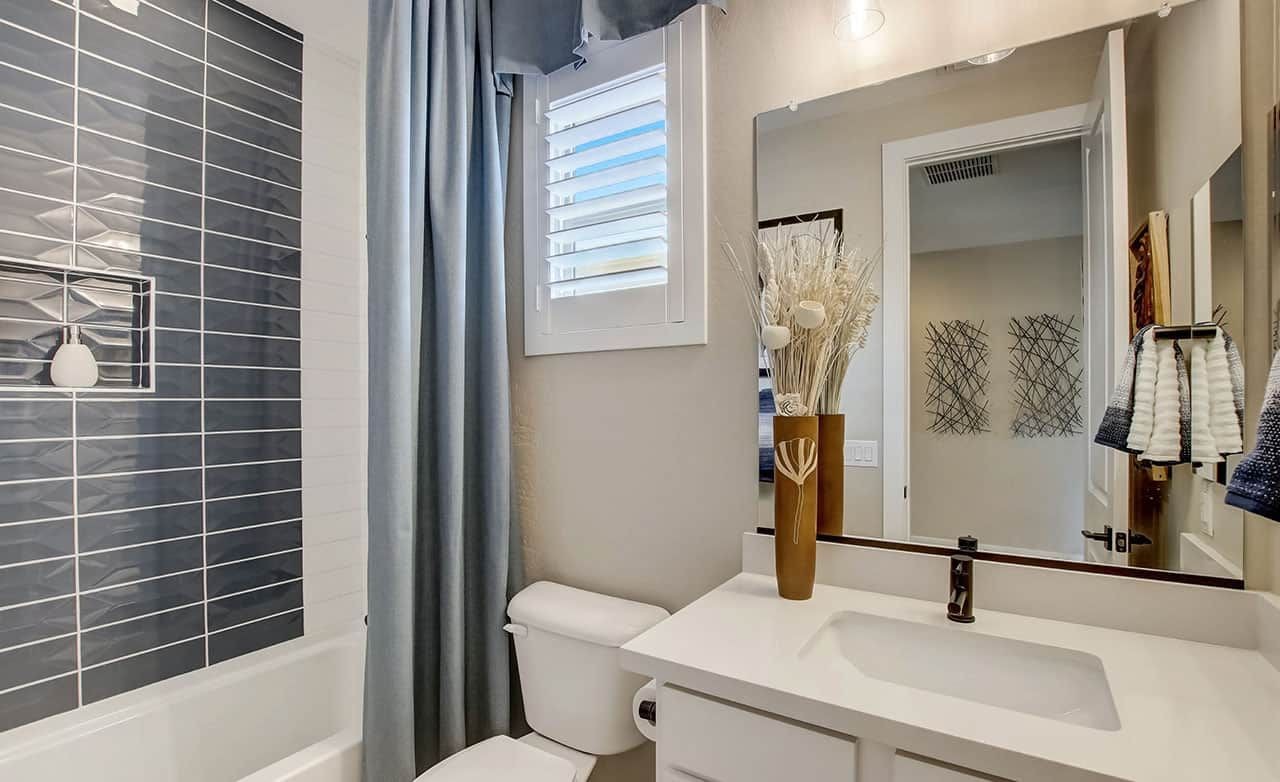 Modern bathroom with gray tile, white vanity, decorative vase, and window at Castillo, Anderson Parc.