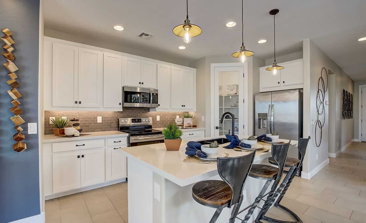 Modern kitchen in Castillo at Anderson Parc featuring white cabinets, pendant lighting, and stainless steel appliances.