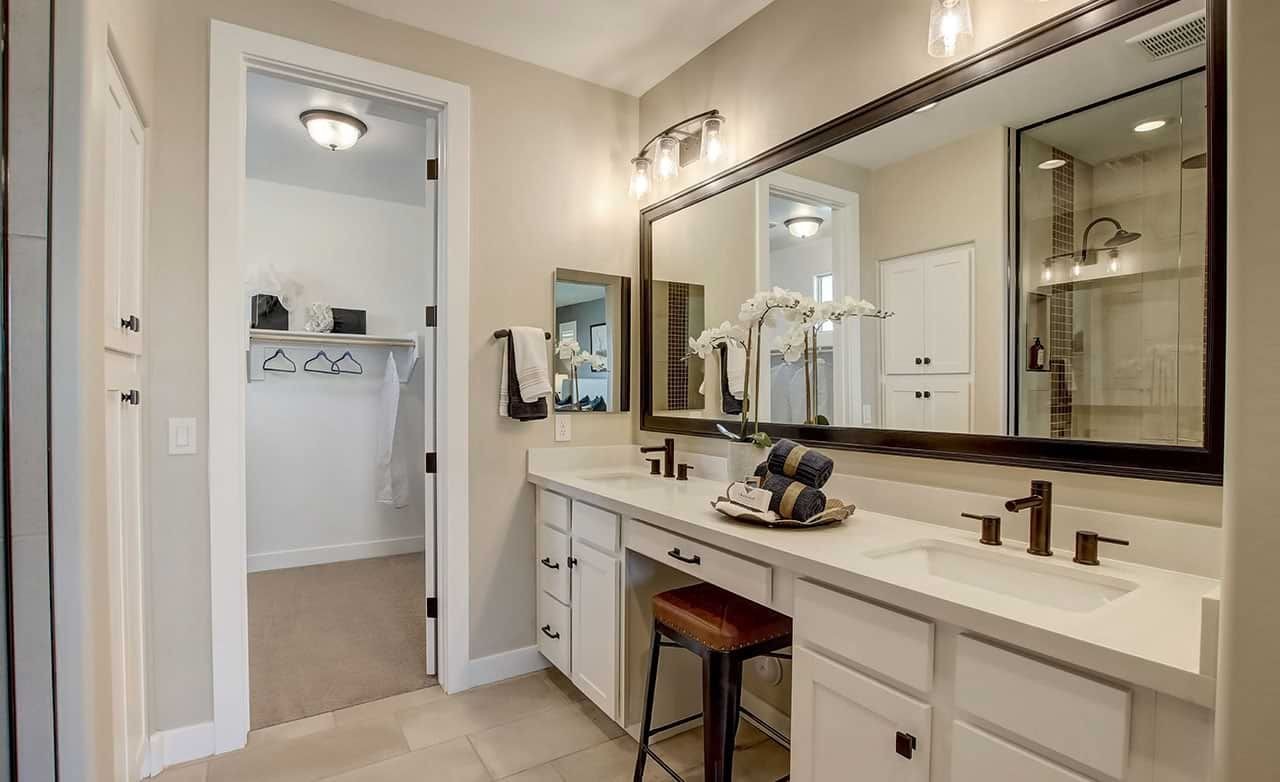 Elegant bathroom with dual sinks, large mirror, bronze fixtures in Anderson Parc. Modern, spacious design.