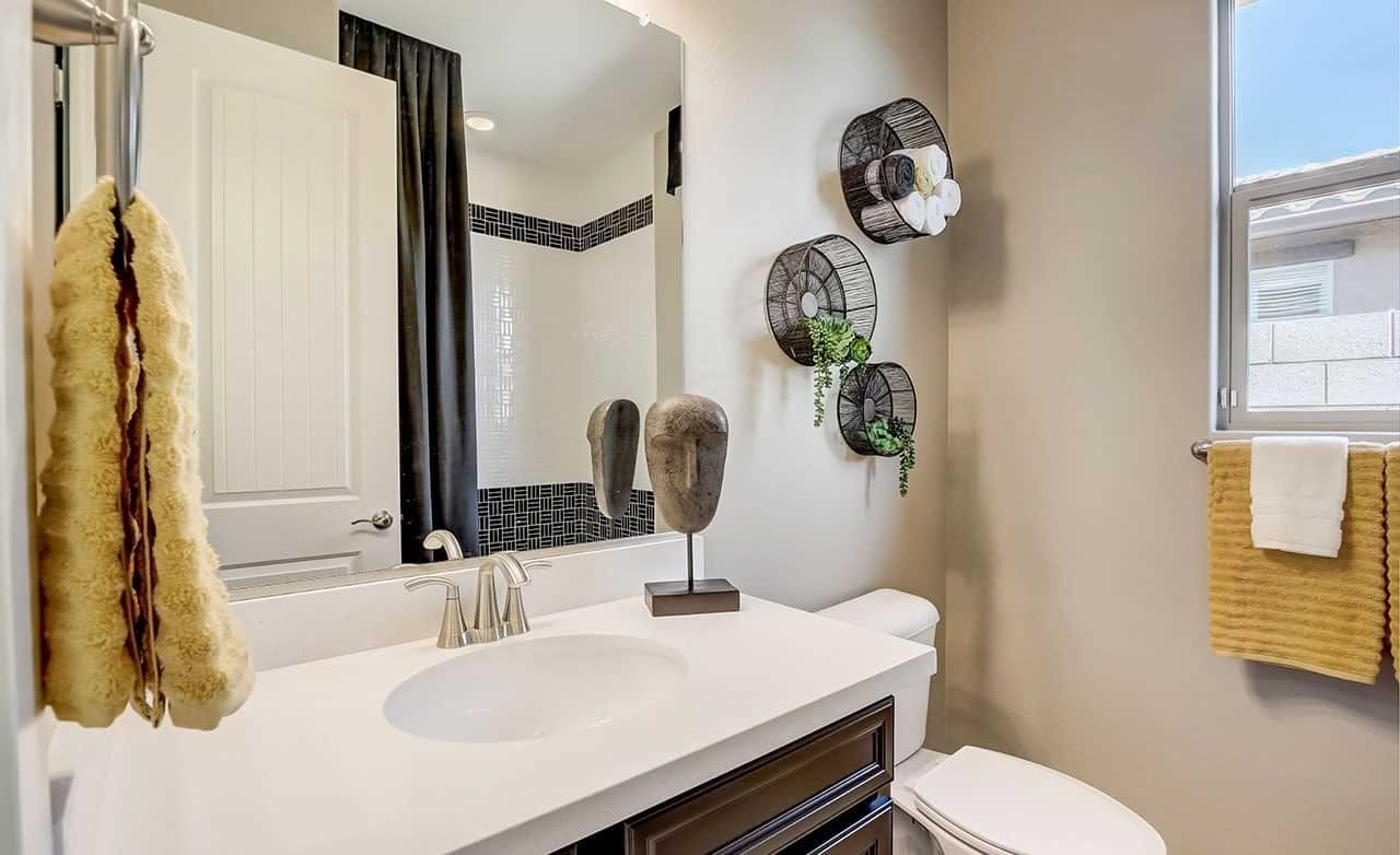 Bathroom in Castillo at Anderson Parc; features white countertop, dark cabinetry, artistic wall decor, window.