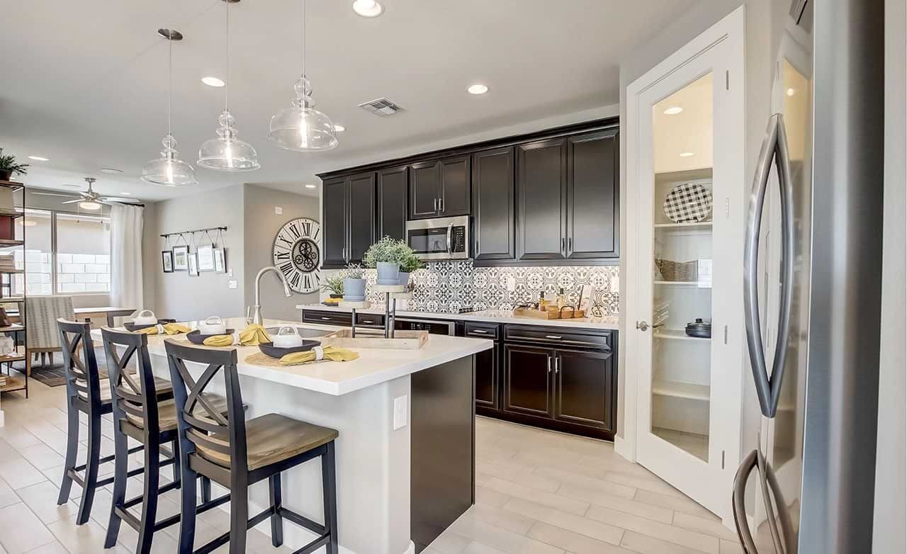 Modern kitchen with island, pendant lights, dark cabinets, patterned backsplash, at Castillo, Anderson Parc.
