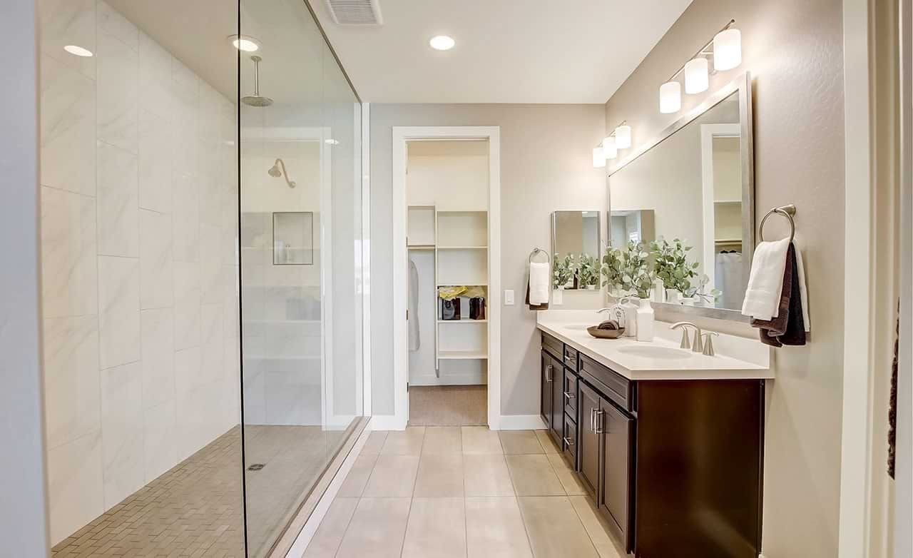 Elegant bathroom with glass shower, double vanity, and large mirror in Anderson Parc home.