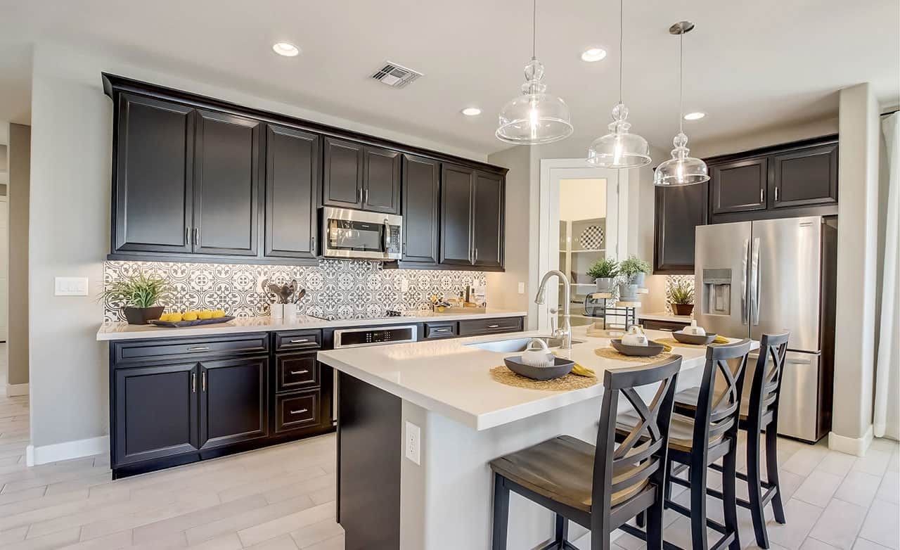 Modern kitchen with black cabinets, patterned backsplash, and island in Castillo at Anderson Parc, Arizona.