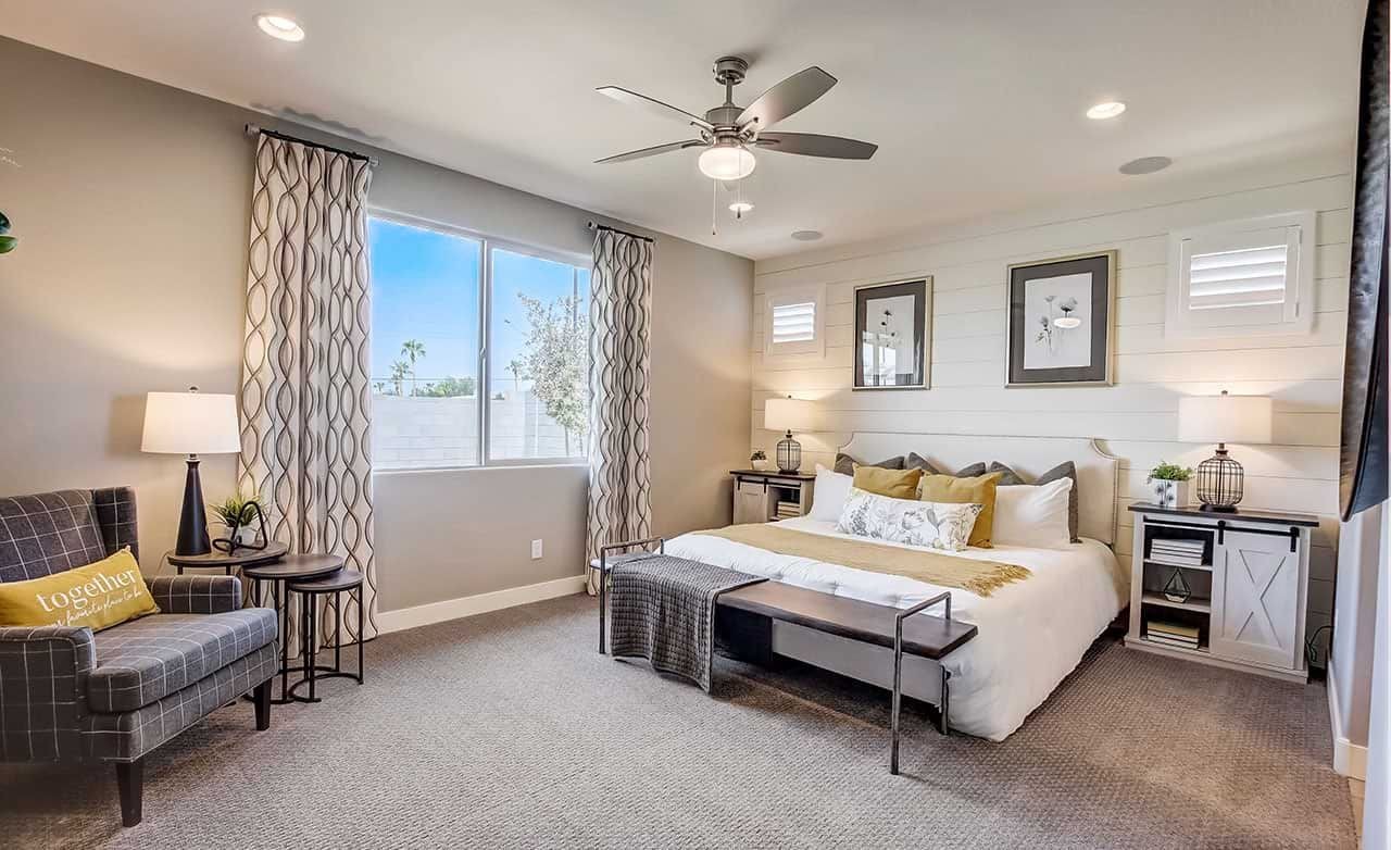 Elegant bedroom with large window, ceiling fan, cozy seating, shiplap wall in Castillo at Anderson Parc.