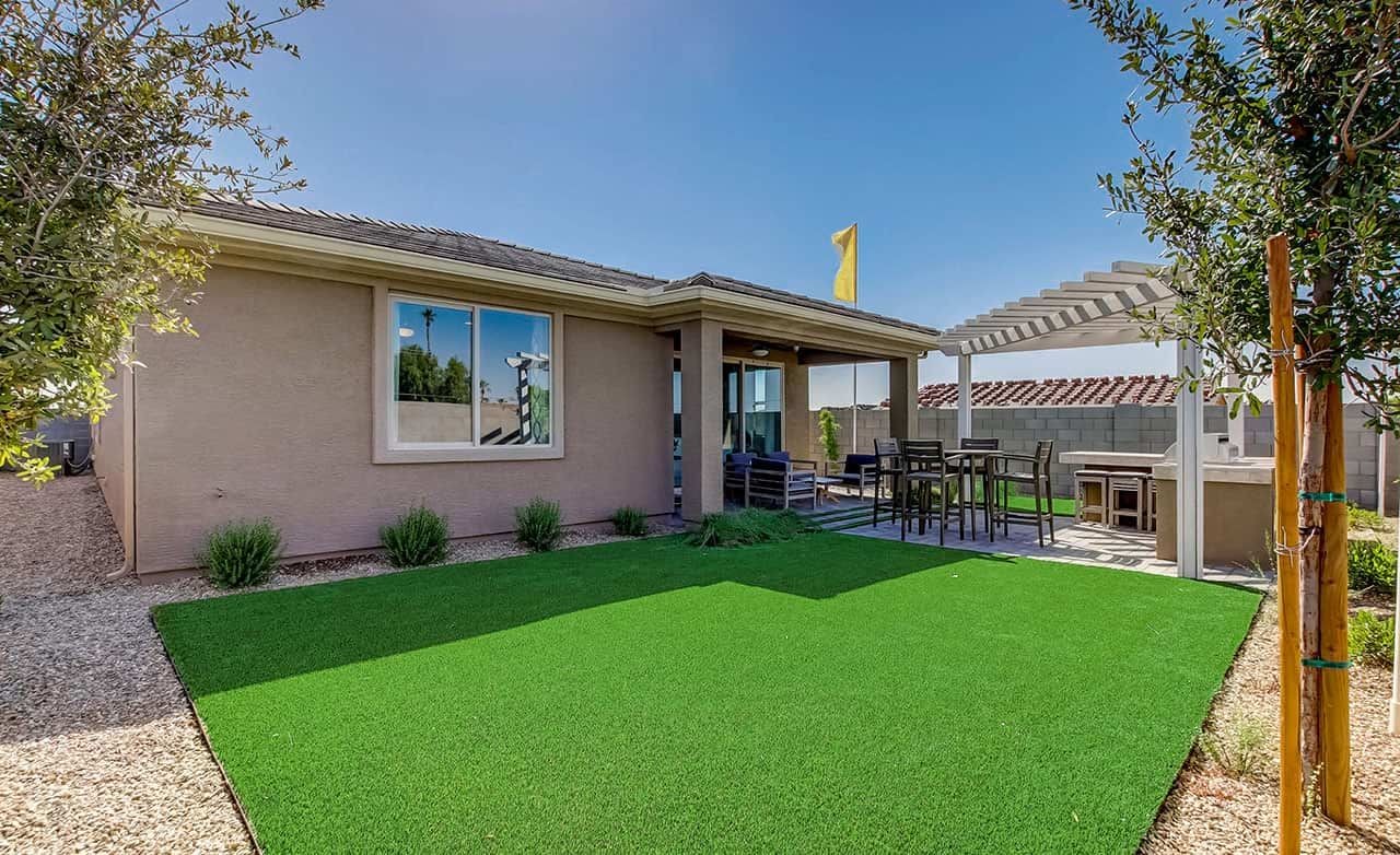 Modern home with pergola-covered patio, lush lawn in Anderson Parc, captures Arizona outdoor living.
