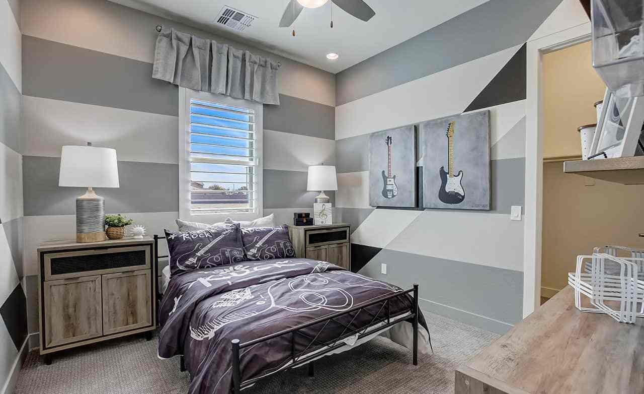 Modern bedroom with striped walls, guitar art, cozy furnishings, in Mirada Crossing community.
