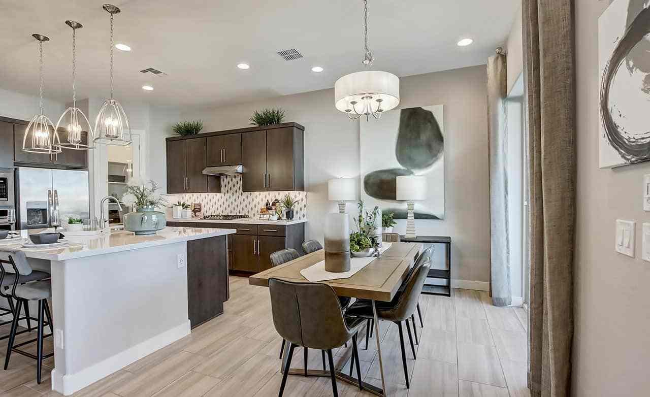 Modern kitchen in Mirada Crossing with island, pendant lights, and wood cabinets. Sleek dining area adjacent.