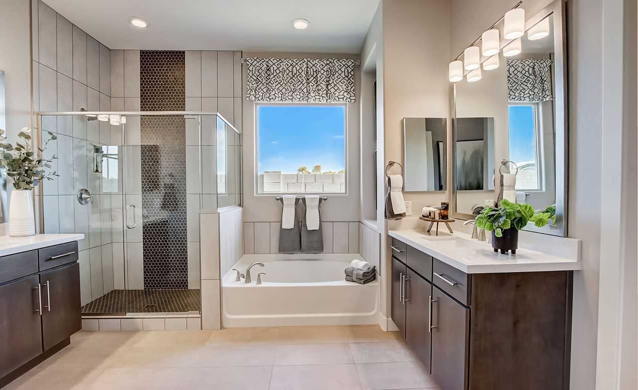 Modern bathroom with sleek dark cabinets, glass shower, and tub in Mirada Crossing. Elegant fixtures, bright window view.