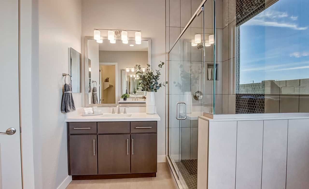 Modern bathroom with glass shower, dark wood vanity, large mirror, in Mirada Crossing.