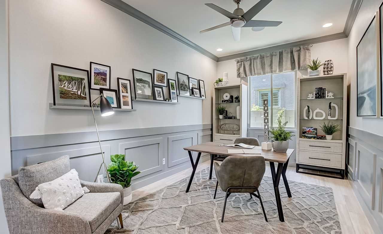 Chic home office with modern decor, framed photos, gray paneling, and large window in Mirada Crossing.