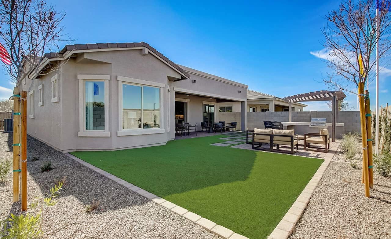 Modern backyard with pergola, paved patio, and artificial grass in Mirada Crossing community. Clear sky backdrop.