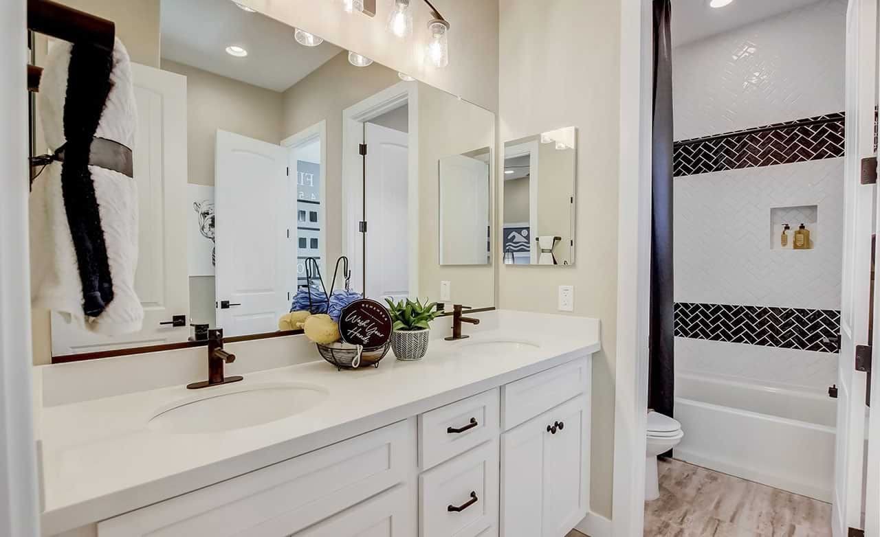 Luxury bathroom in Mirada Crossing with double vanity, white cabinets, decorative tile, modern fixtures.