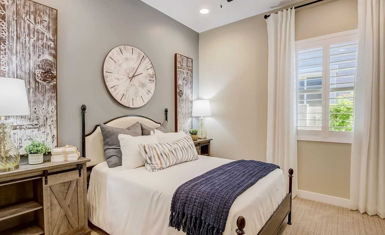 Elegant bedroom with rustic decor, large clock, wood accents, Mirada Crossing luxury home. Neutral palette, natural light.