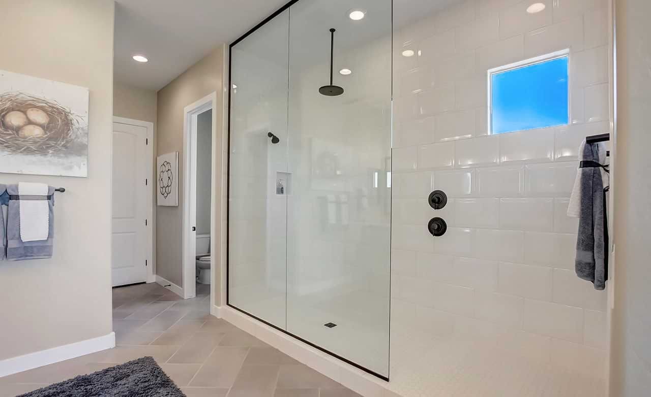 Luxurious glass-enclosed shower with modern fixtures; elegant tile work; Mirada Crossing location.