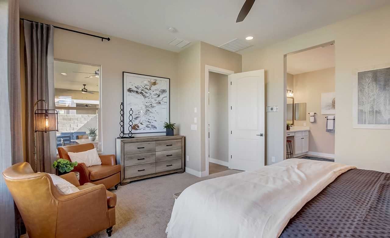 Elegant bedroom in Mirada Crossing, featuring leather chairs, modern art, and en-suite bathroom.