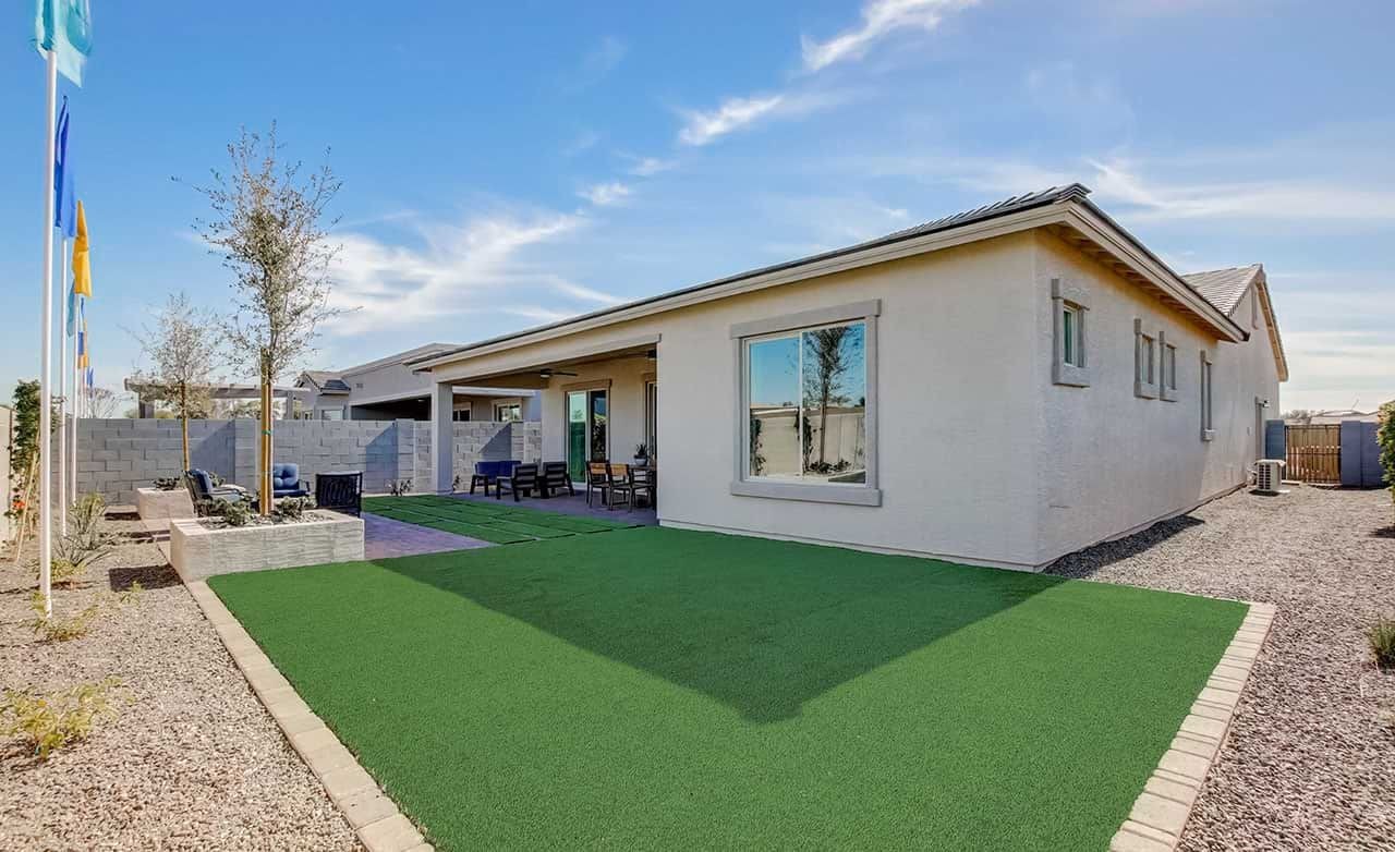 Modern house with synthetic lawn, patio, and brick fence in Mirada Crossing community, Arizona.