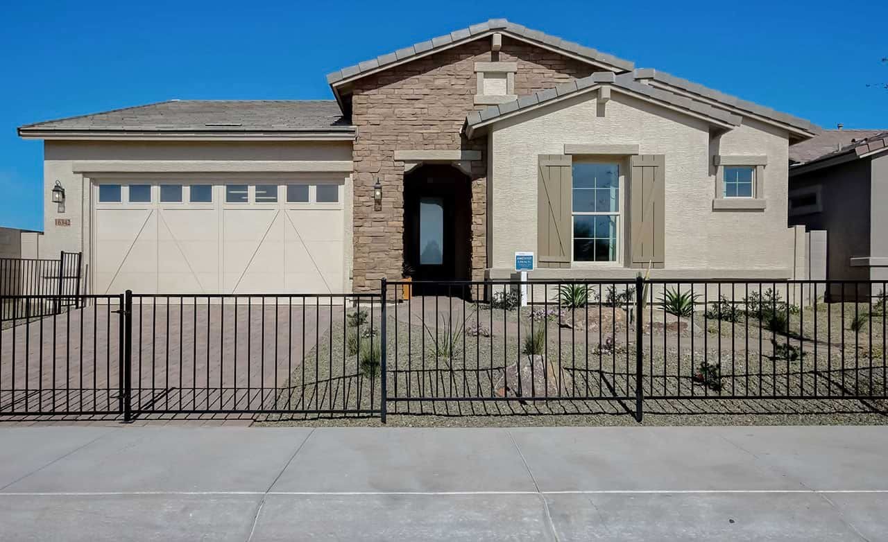 Single-story stone and stucco home with desert landscaping, fenced yard, located in Mirada Crossing community.