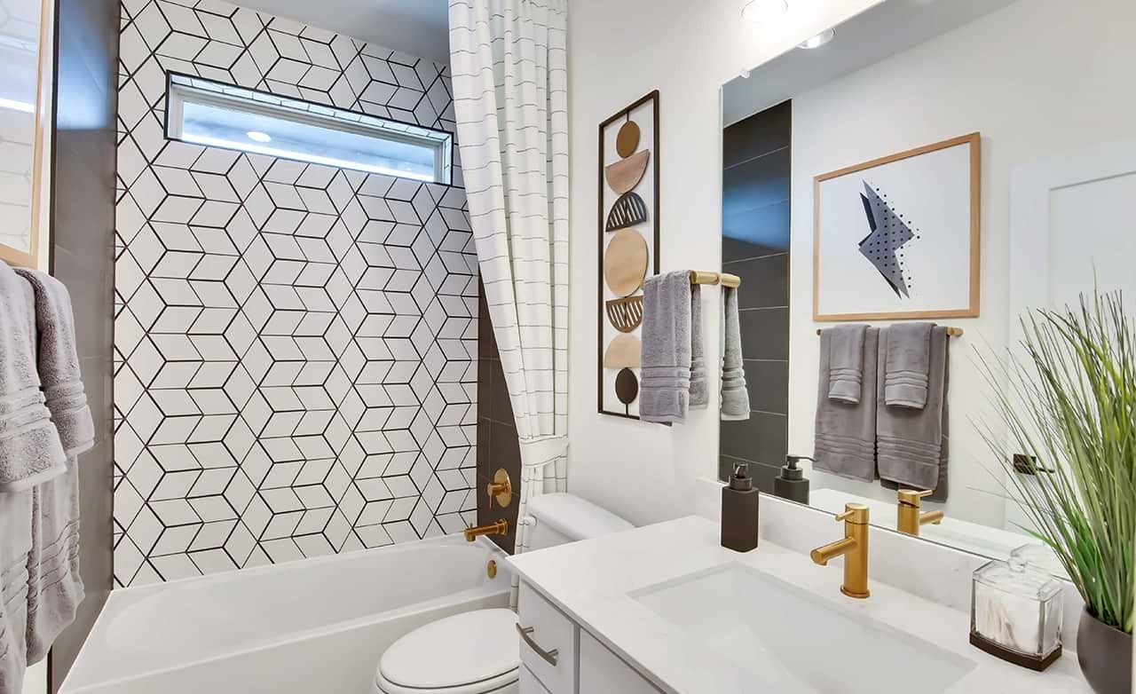 Modern bathroom with gold fixtures, geometric tiles, and minimalist decor in Oaks at San Gabriel, Texas.