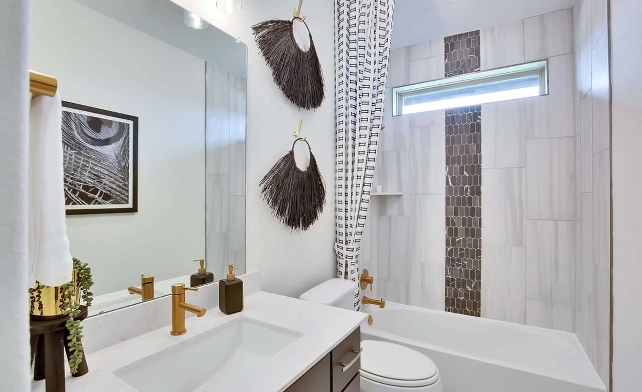 Modern bathroom with marble tiles, gold fixtures, and artistic decor at Oaks at San Gabriel.