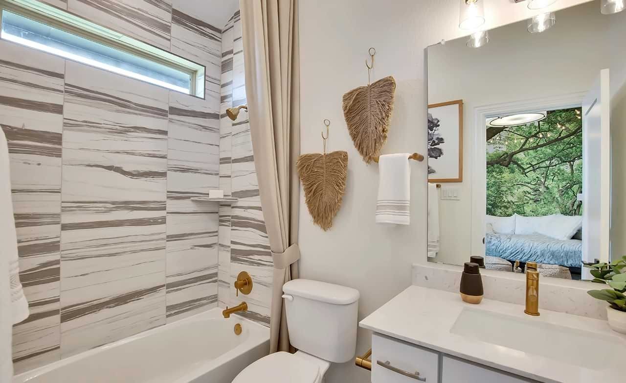 Elegant bathroom with marble tiles, gold fixtures, and natural decor in Oaks at San Gabriel home.