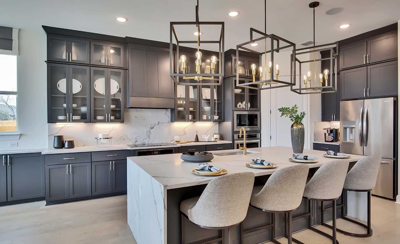 Luxury kitchen with marble island, pendant lights, and dark cabinets in Oaks at San Gabriel community.