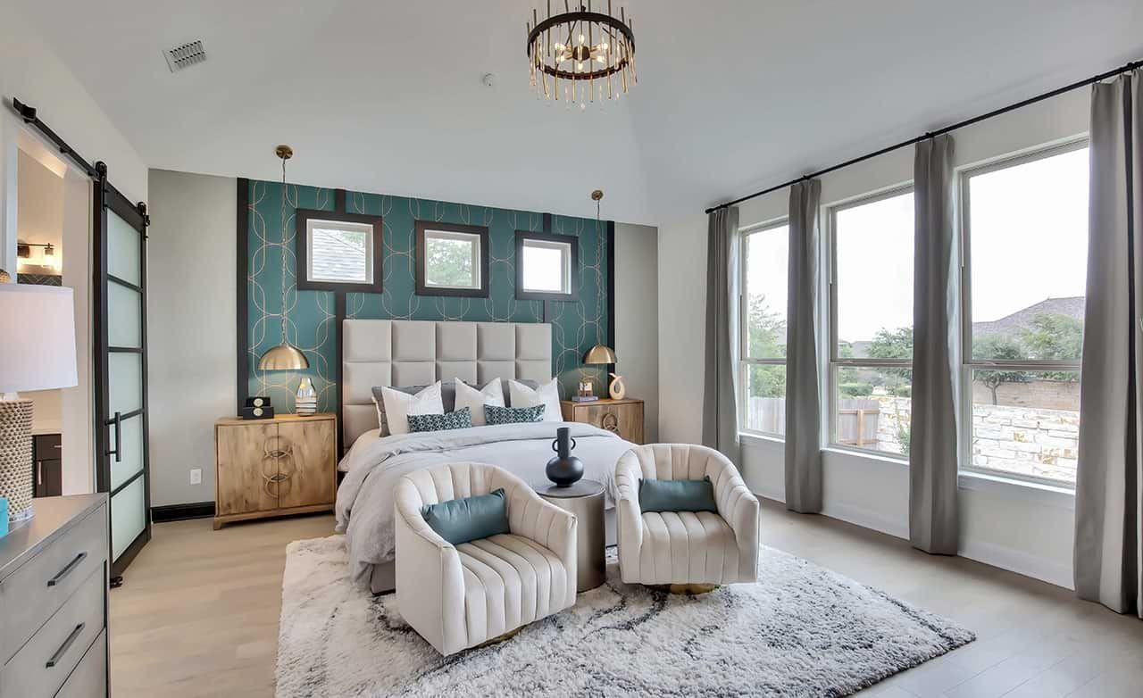 Elegant bedroom with large windows, modern chandelier, and plush decor in Oaks at San Gabriel, Texas.