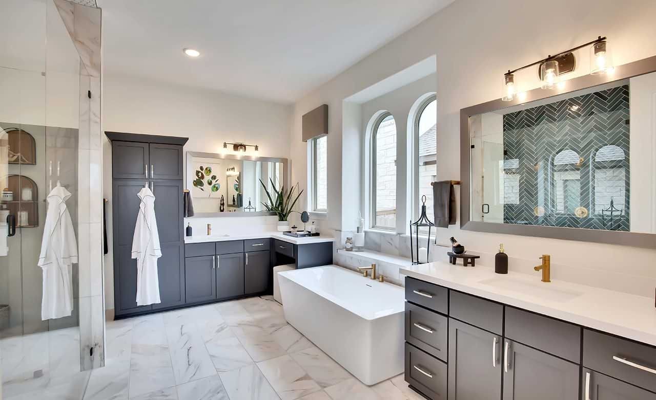 Luxurious bathroom features freestanding tub, herringbone tile, and dark cabinets in Oaks at San Gabriel, Texas.
