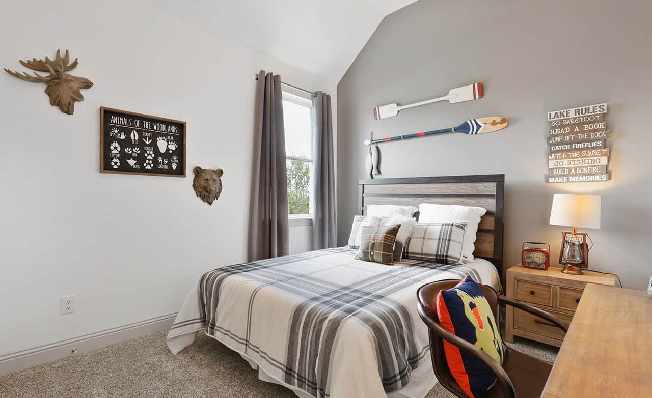 Cozy bedroom with plaid bedding, wood accents, and animal-themed decor in Thompson Farms community.